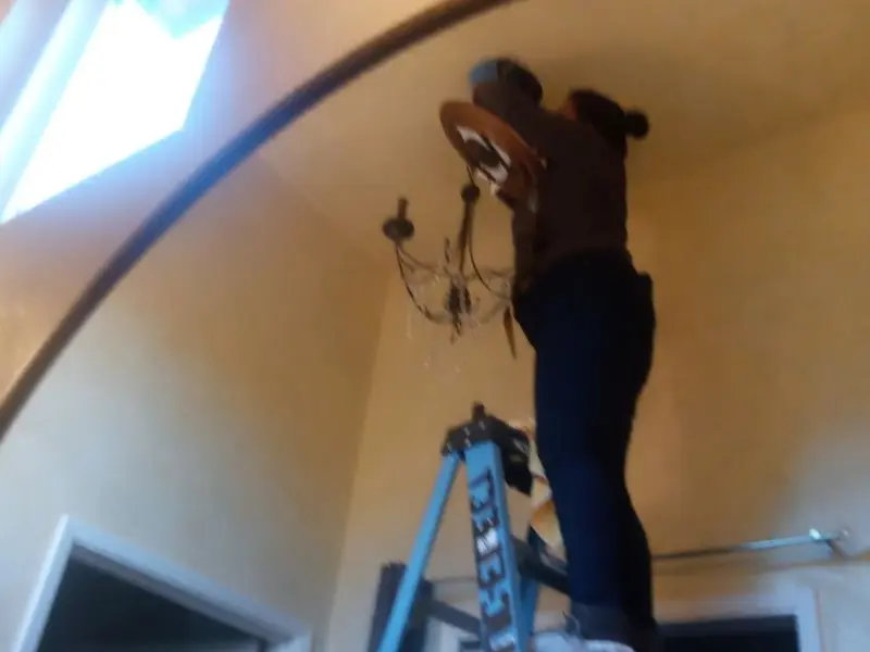 Electrician installing a chandelier in a Cambria residence